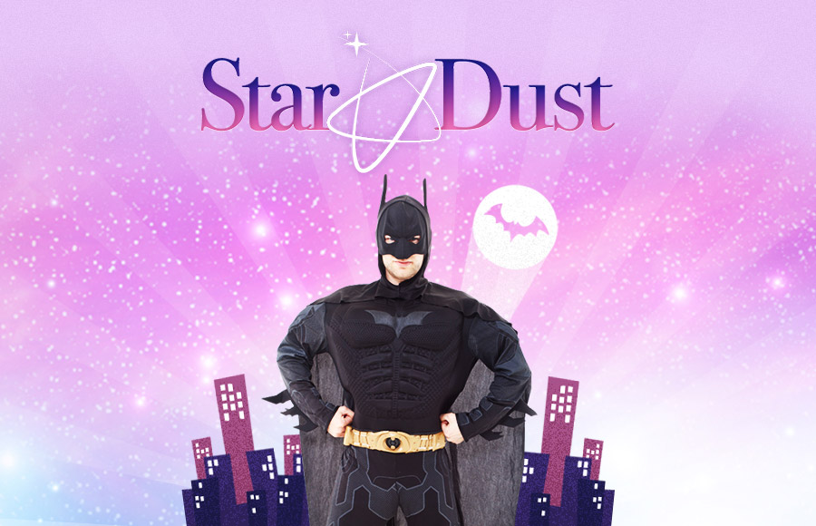 A man entertainer dressed in a Batman costume stands posing in a glittery graphic for Star Dust Kids Entertainment. A cityscape silhouette and a spotlight circle with the Bat-Signal are behind him, and images of smiling children are visible in the foreground